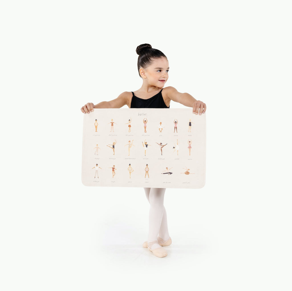 Image of a small girl in ballerina attire holding a mat