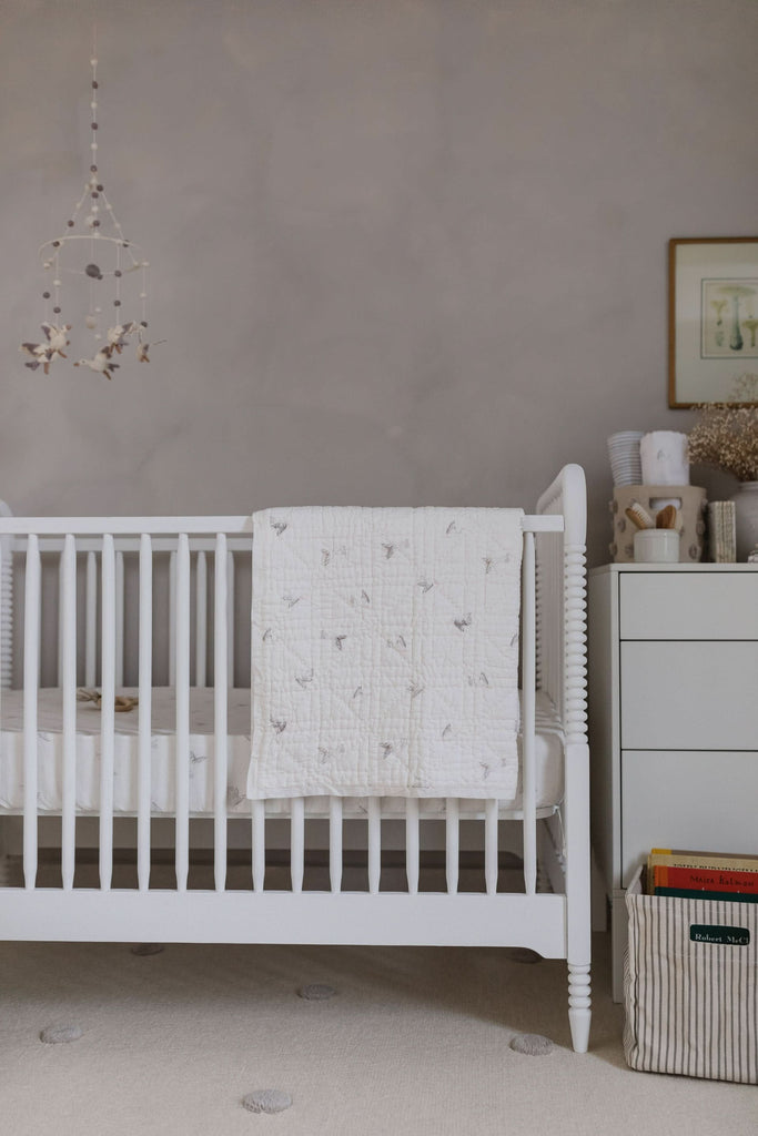 image of a nursery room with white crib and swaddle